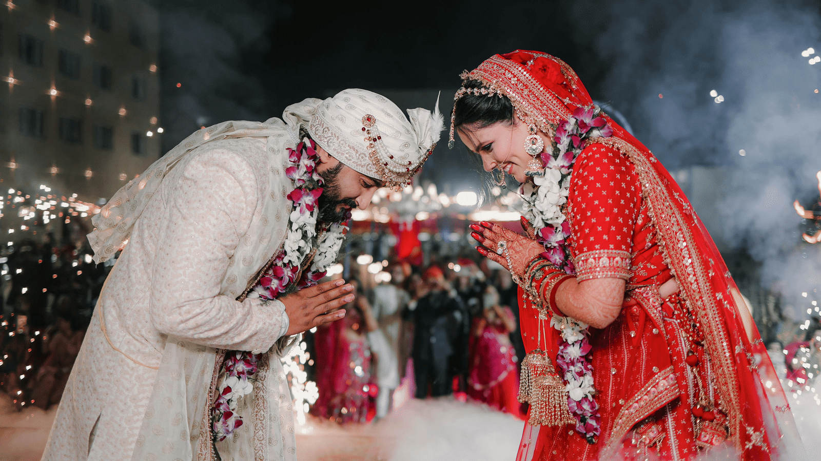 Indian bride and groom performing a wedding ritual under decorative lights.