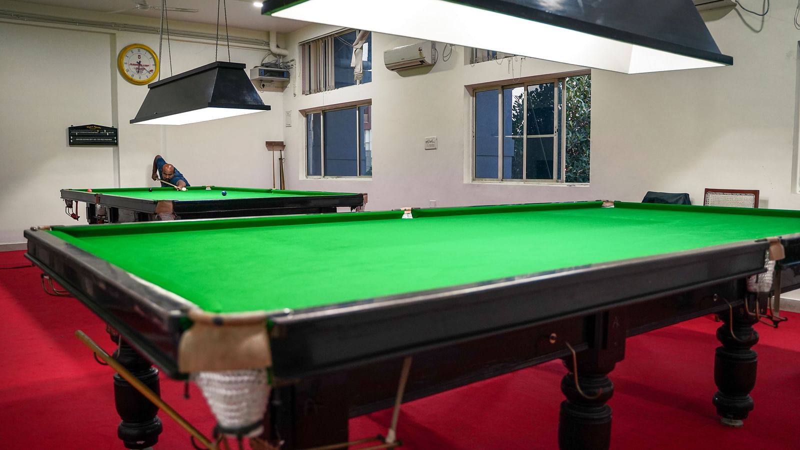 Multiple snooker tables with green felt and dedicated overhead lighting in a spacious room at BNGV Grandeur Hotel and Banquets.