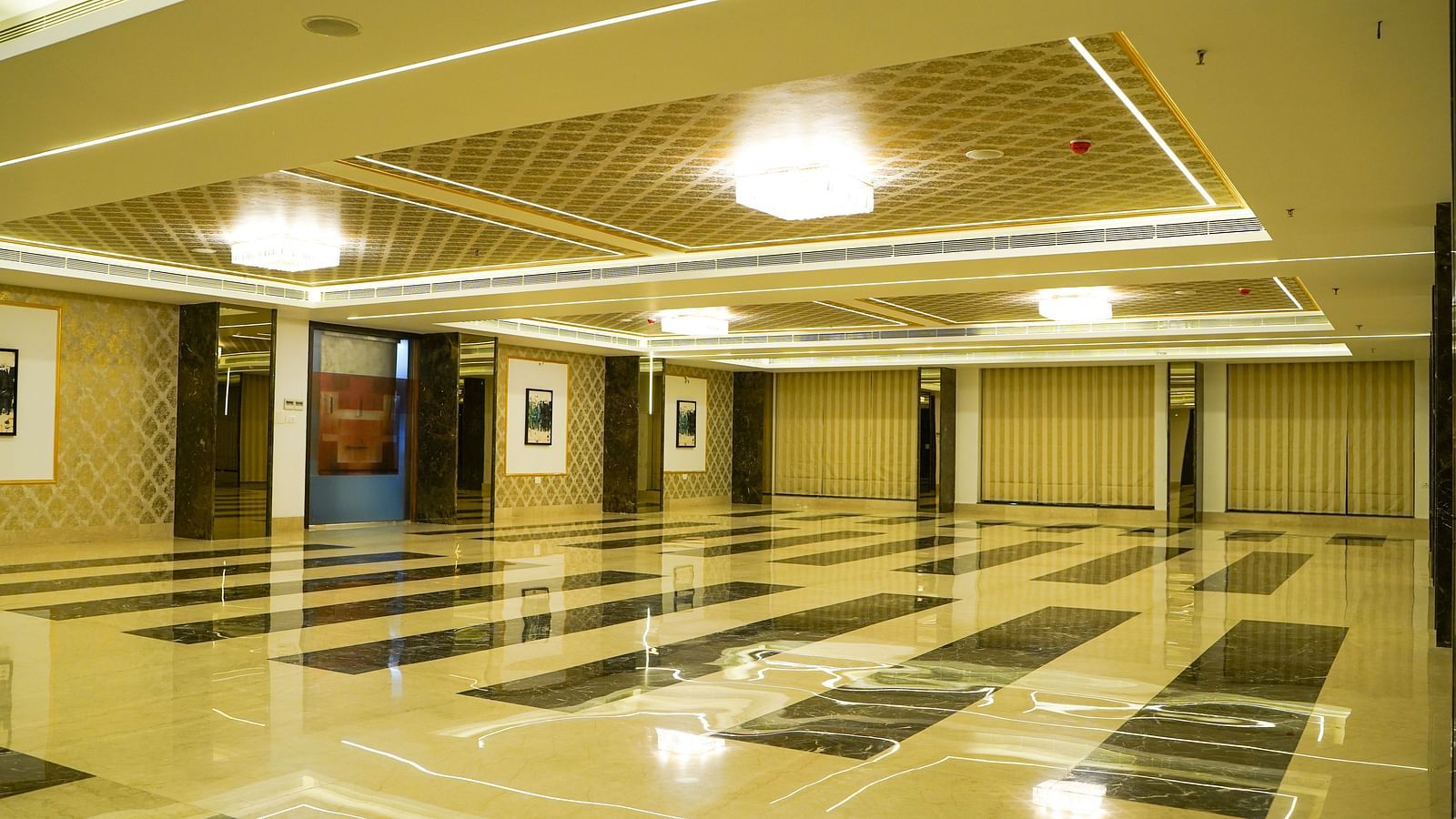 A wide view of a spacious banquet hall with polished, patterned floor tiles and bright overhead lighting.