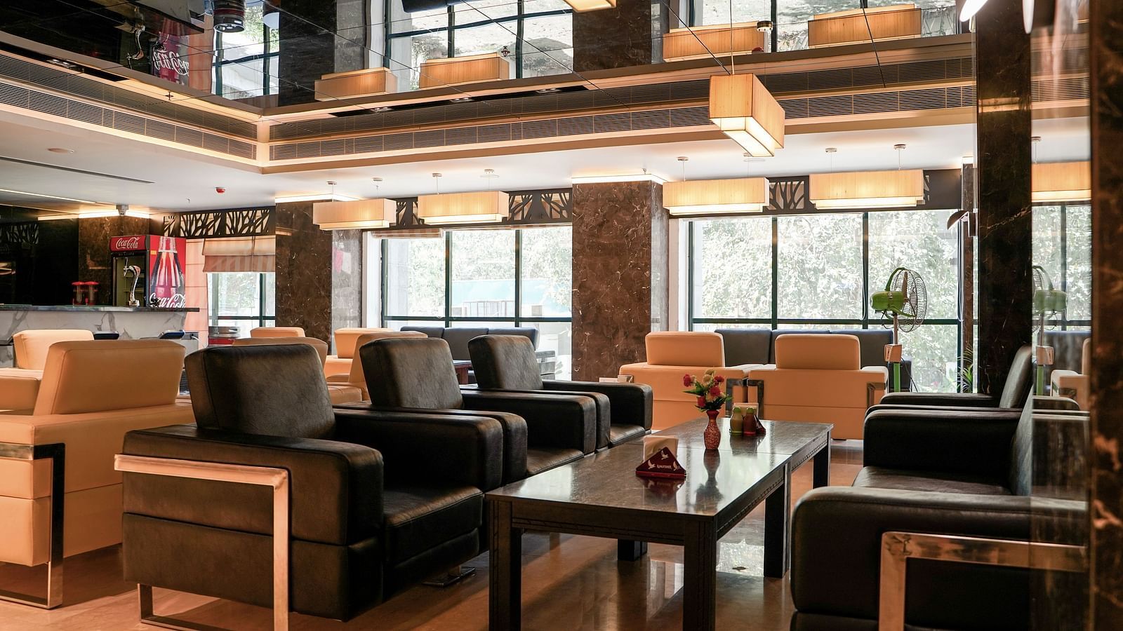 A sophisticated lounge or common area with dark, comfortable seating and wooden tables, reflecting the interior design of BNGV Grandeur Hotel and Banquets.