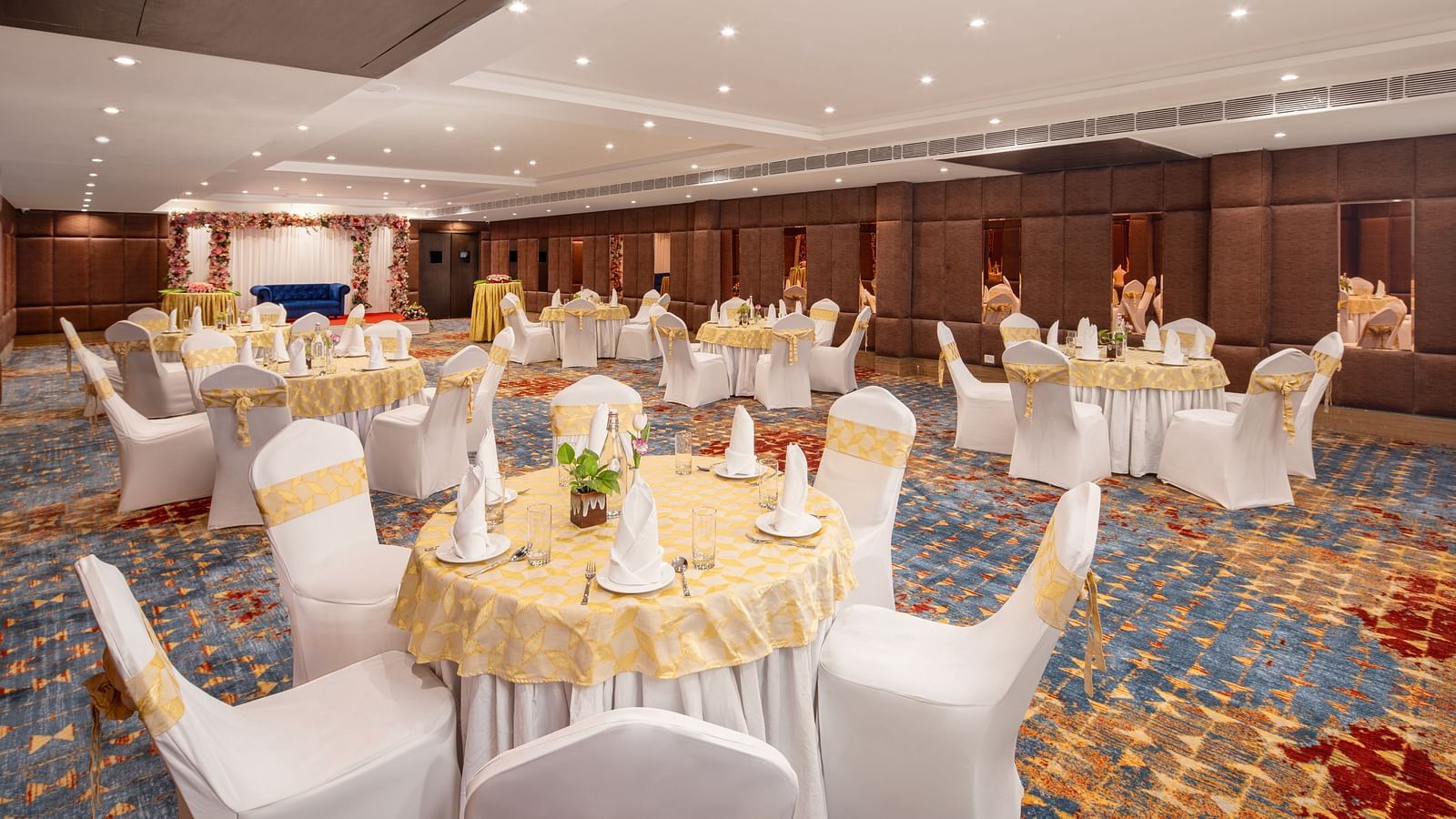 An image of a banquet hall with several chairs and table sets spread out - Brij Eternity, Vrindavan