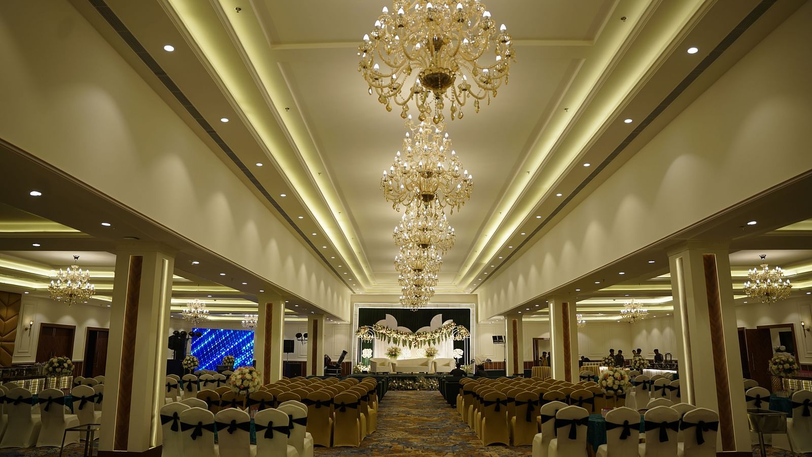 Grand banquet hall at Brij Eternity, Vrindavan  | An elegant, well-lit banquet hall with luxurious chandeliers and a spacious seating arrangement