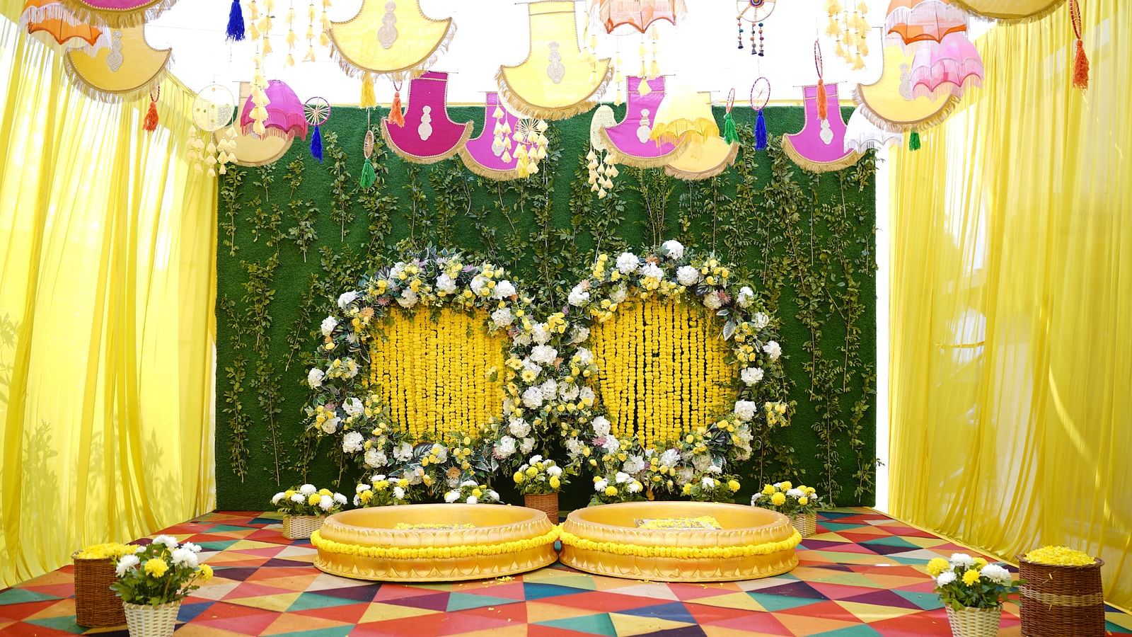 Brij Eternity, Vrindava |  A stage with floral backdrops, golden seating, and vibrant yellow drapery for wedding ceremonies.