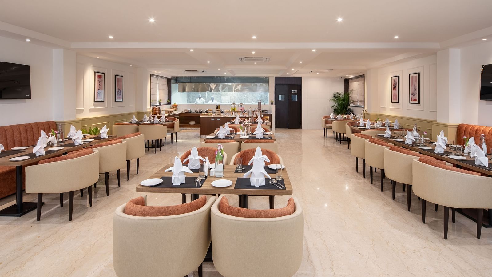 An image of a dining space with sofa chairs, centre table with hand towels and cutlery, and a buffet served at one corner - Brij Eternity, Vrindavan