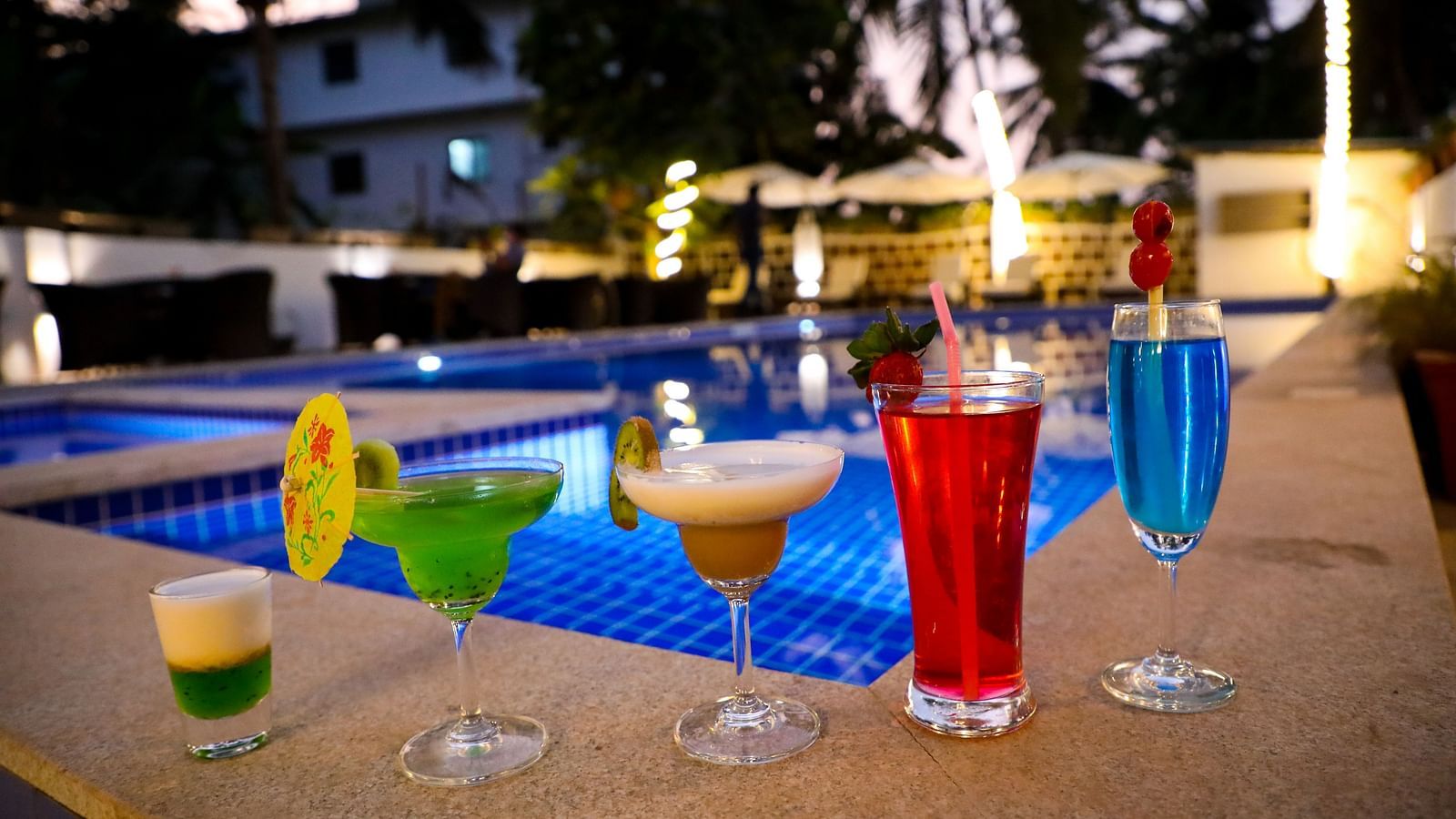 Image of five glasses of drinks placed on the side of a pool at Calux Grand Baga.