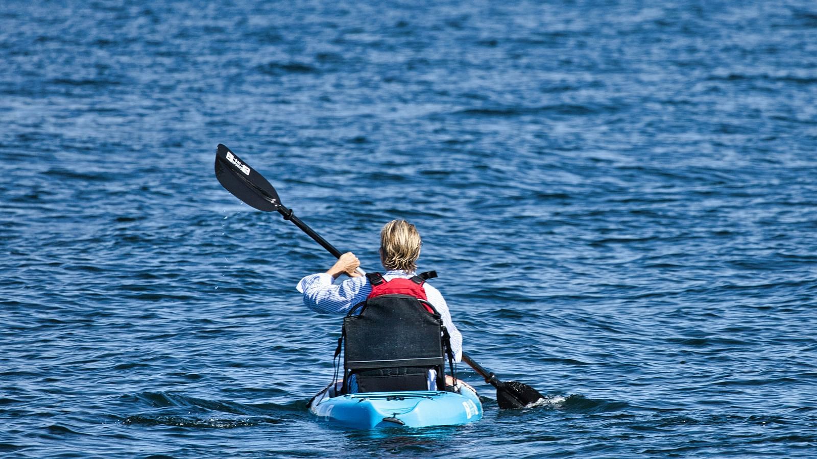A solitary person kayaking in a waterbody as seen from afar