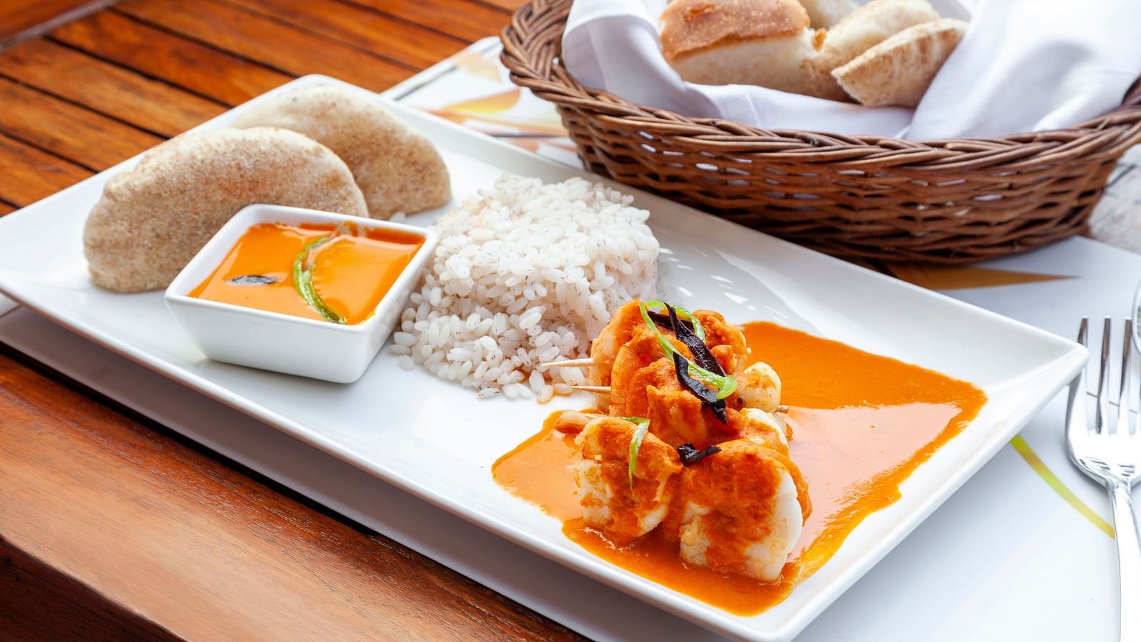 a plate with rice, curry and other side dishes kept on the table - Caravela Beach Resort Goa