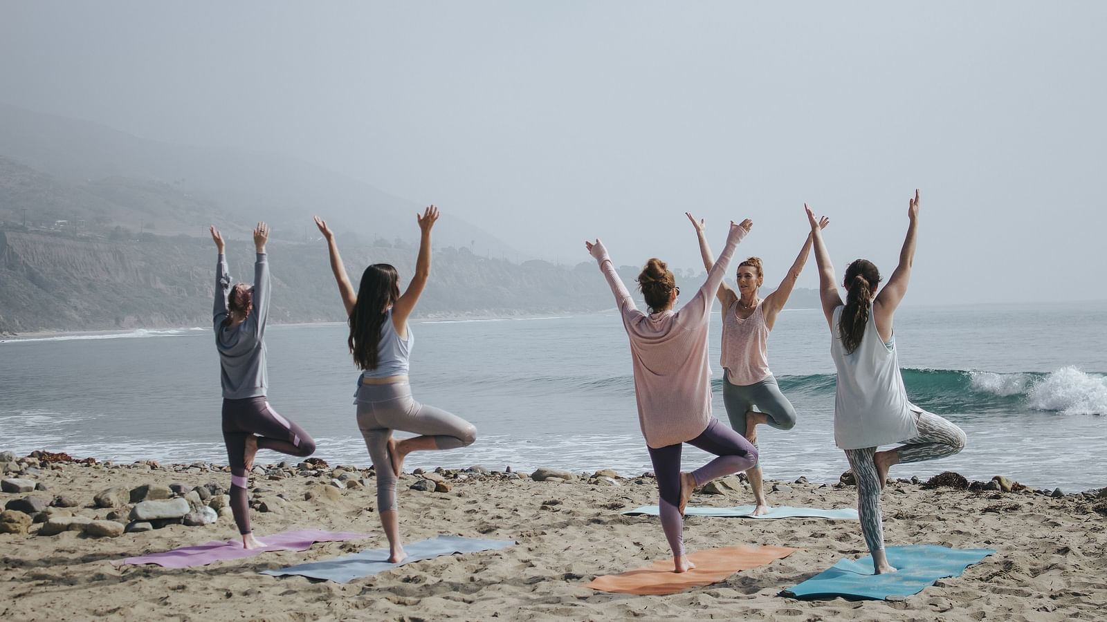 People doing group yoga at beach looking in to the horizon