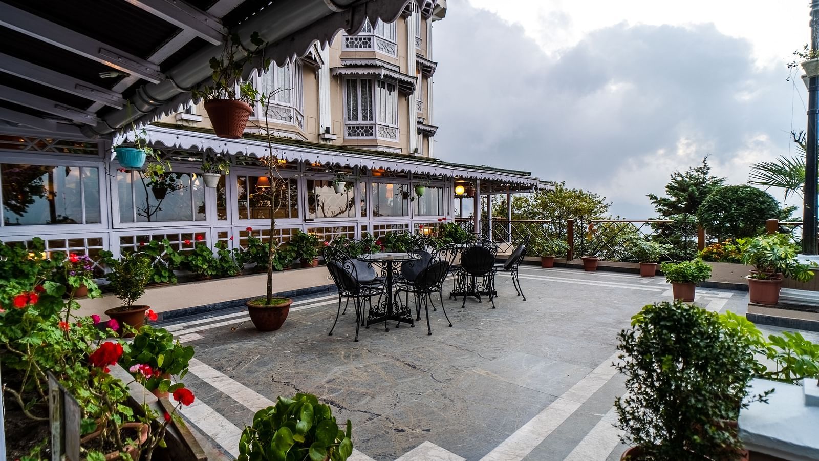 Outdoor dining area at Cedar Inn, Darjeeling, set against the hotel’s facade and scenic hillside views.