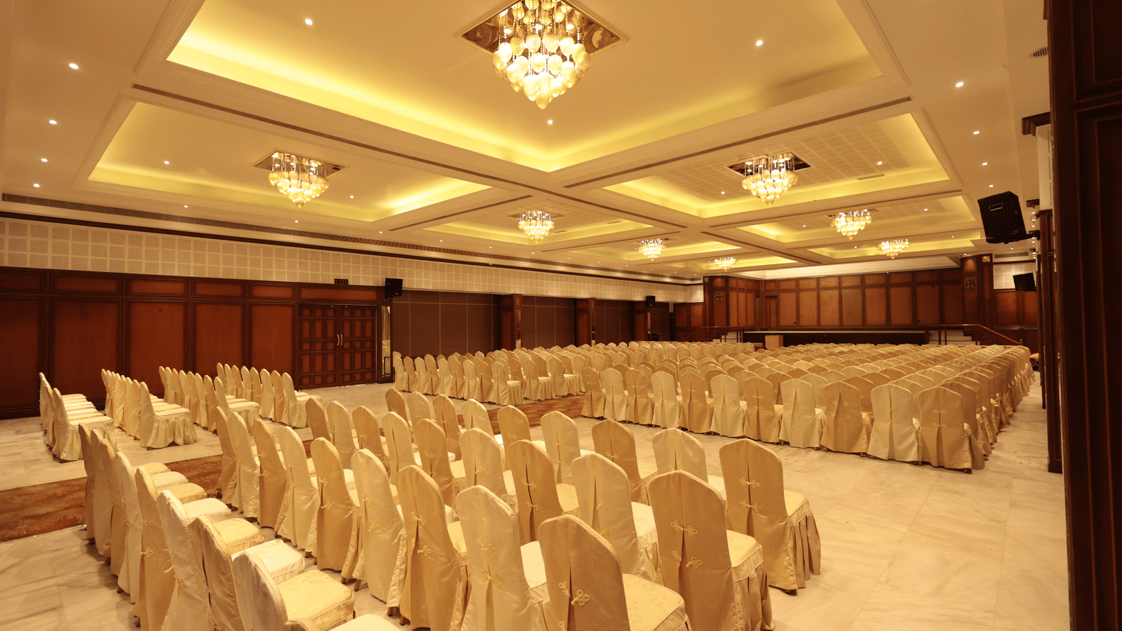 A diagonal view of the banquet hall from behind, with decorated chairs and yellow lighting | Cenneys Gateway