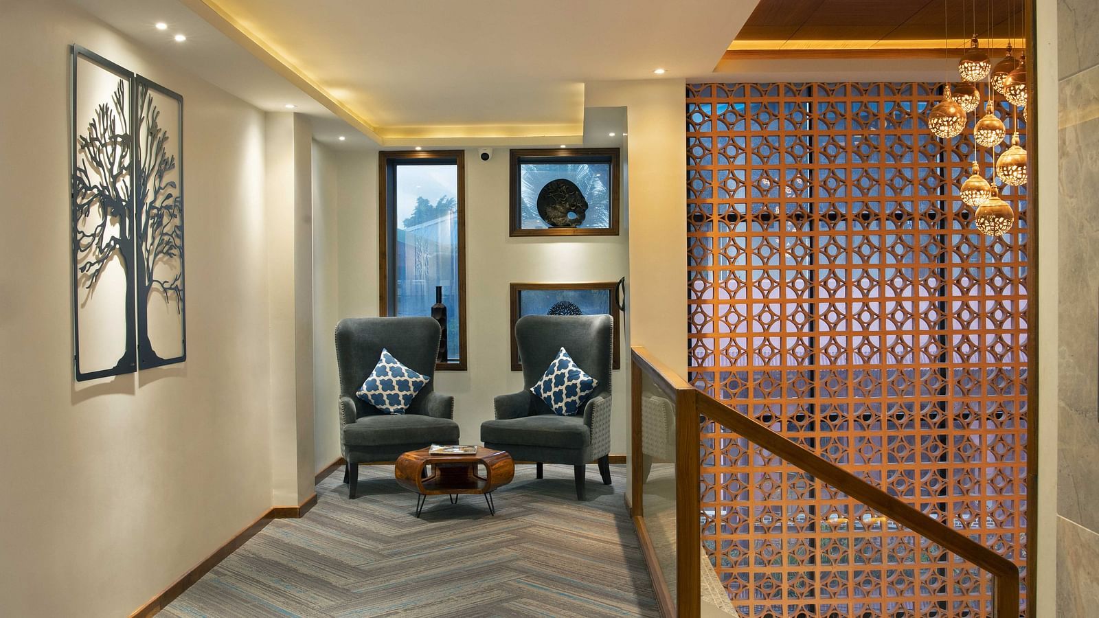 A lounge area at Coral Reef Hotel and Spa in Port Blair featuring two one seater couches placed next to each other and an ottoman on the floor