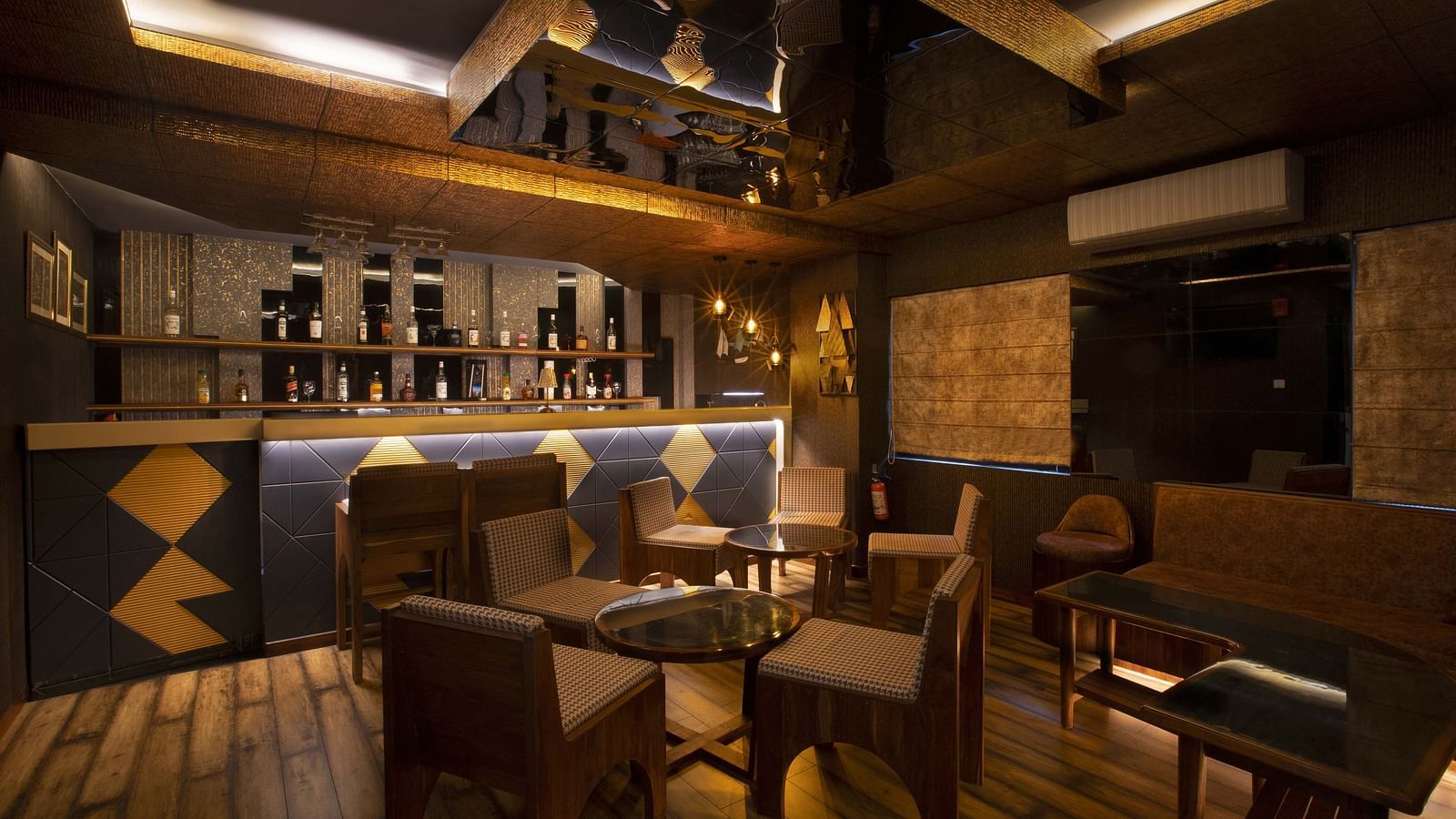 Image of the restaurant at Coral Reef Hotel & Spa in Port Blair showcasing tables arranged next to the bar counter under dim lighting