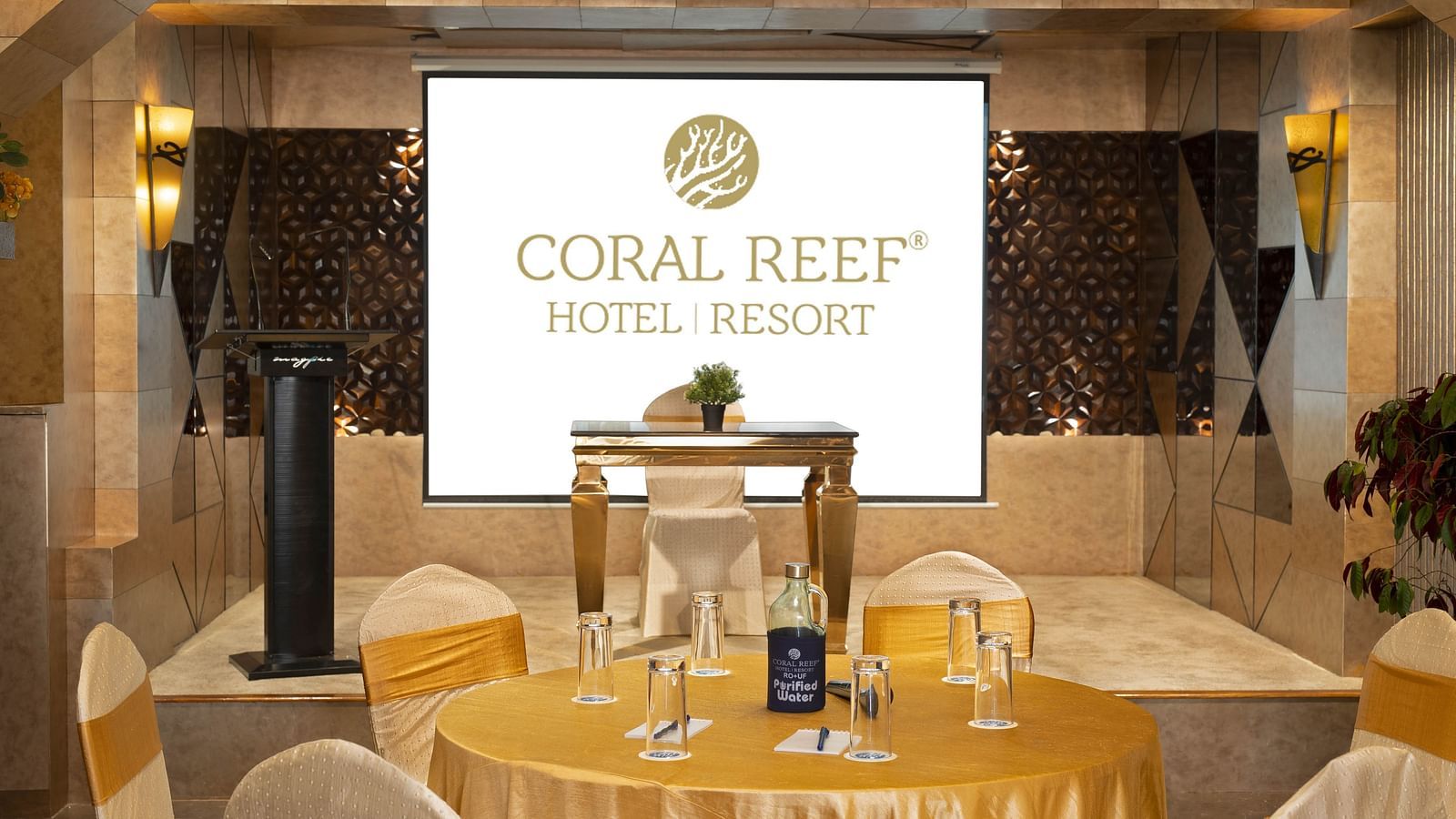 Image of Mosaic Hall at Coral Reef Hotel and Spa in Port Blair featuring seating arrangement with golden fabrics in front of the projector screen 