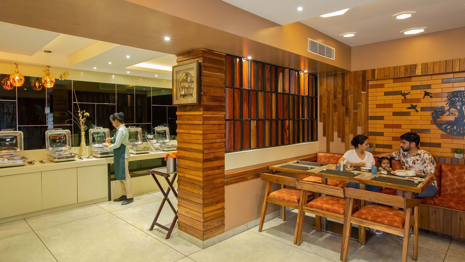 Image of two people along with a child in the middle dining at Honeycomb Restaurant at Coral Reef Hotel & Spa in Port Blair