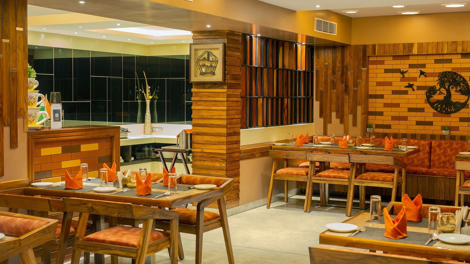 Image of the interiors of Honeycomb Restaurant at Coral Reef Hotel & Spa in Port Blair under warm lighting and walnut furniture 