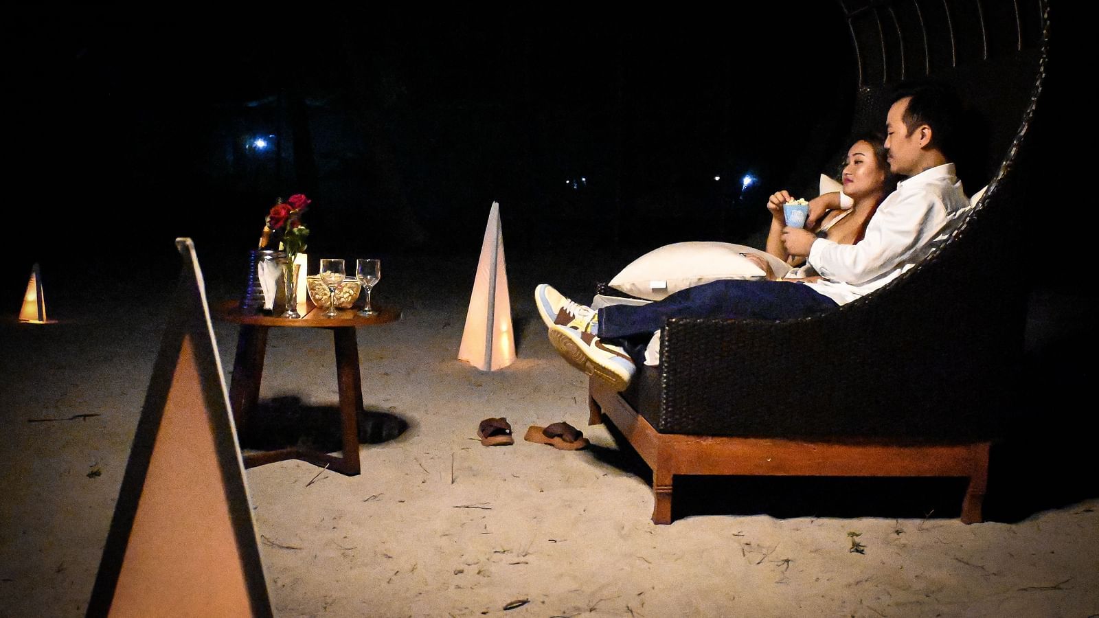 A couple sharing popcorn sitting in a couch setting with wine and roses in front of them - Coral Reef Resort & Spa, Havelock