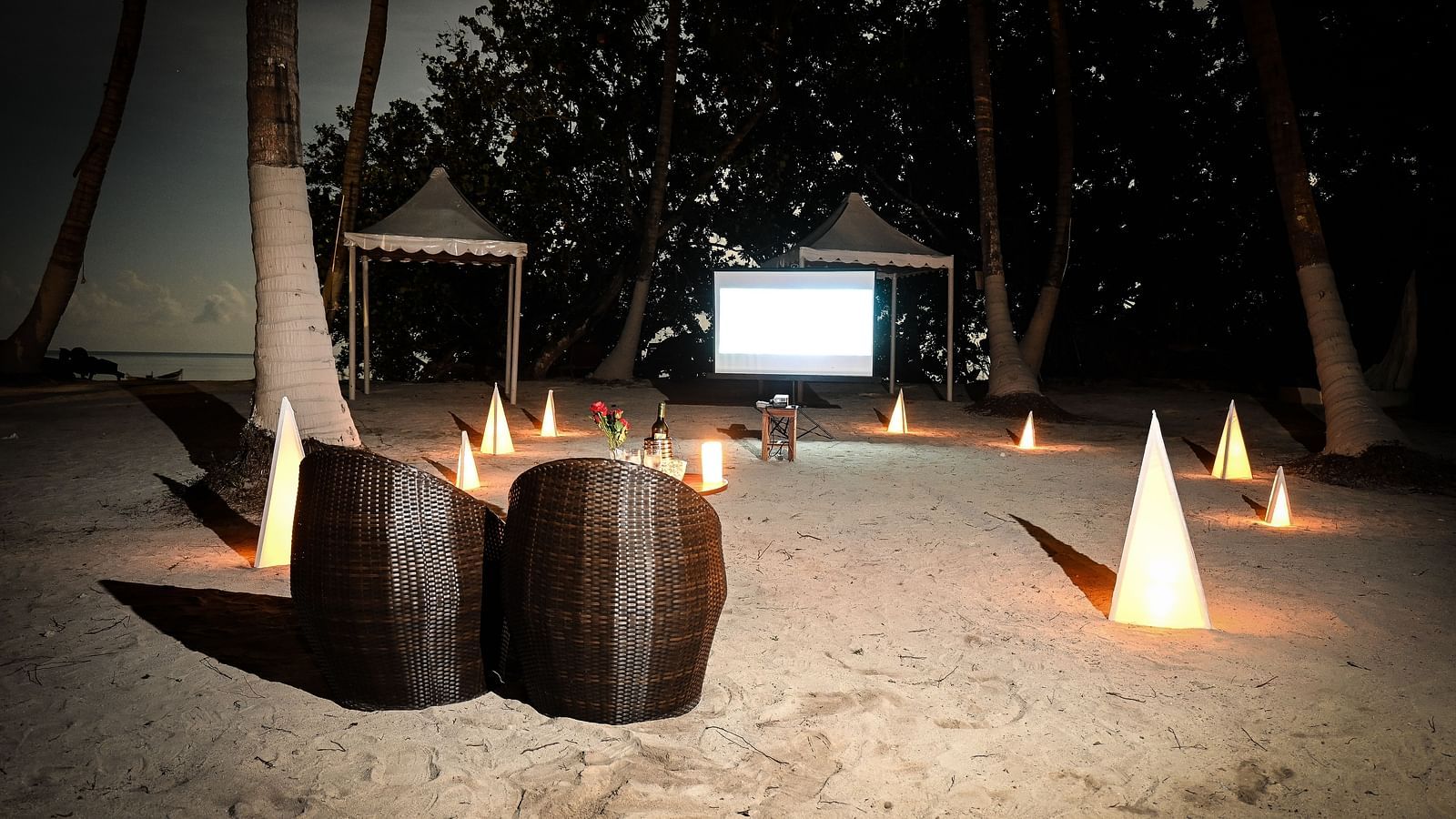 Chairs on the beach with a projector playing on the white screen in the background - Coral Reef Resort & Spa, Havelock