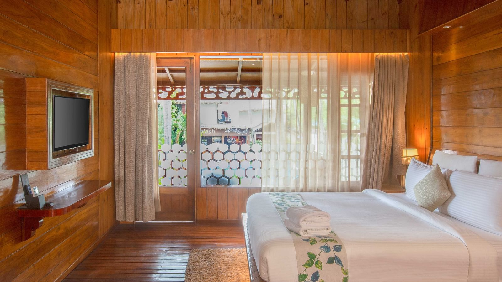 Image of Coral Turquoise at Coral Reef Resort and Spa in Havelock featuring a plush bed with a TV mounted on the wall in front of it and the doorway to the balcony
