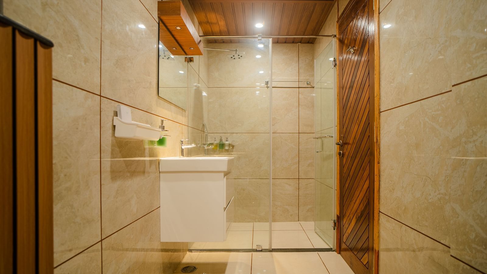 Another view of a bathroom in a hotel with white tiles and a large sink with toiletries placed on it - Coral Reef Resort & Spa, Havelock