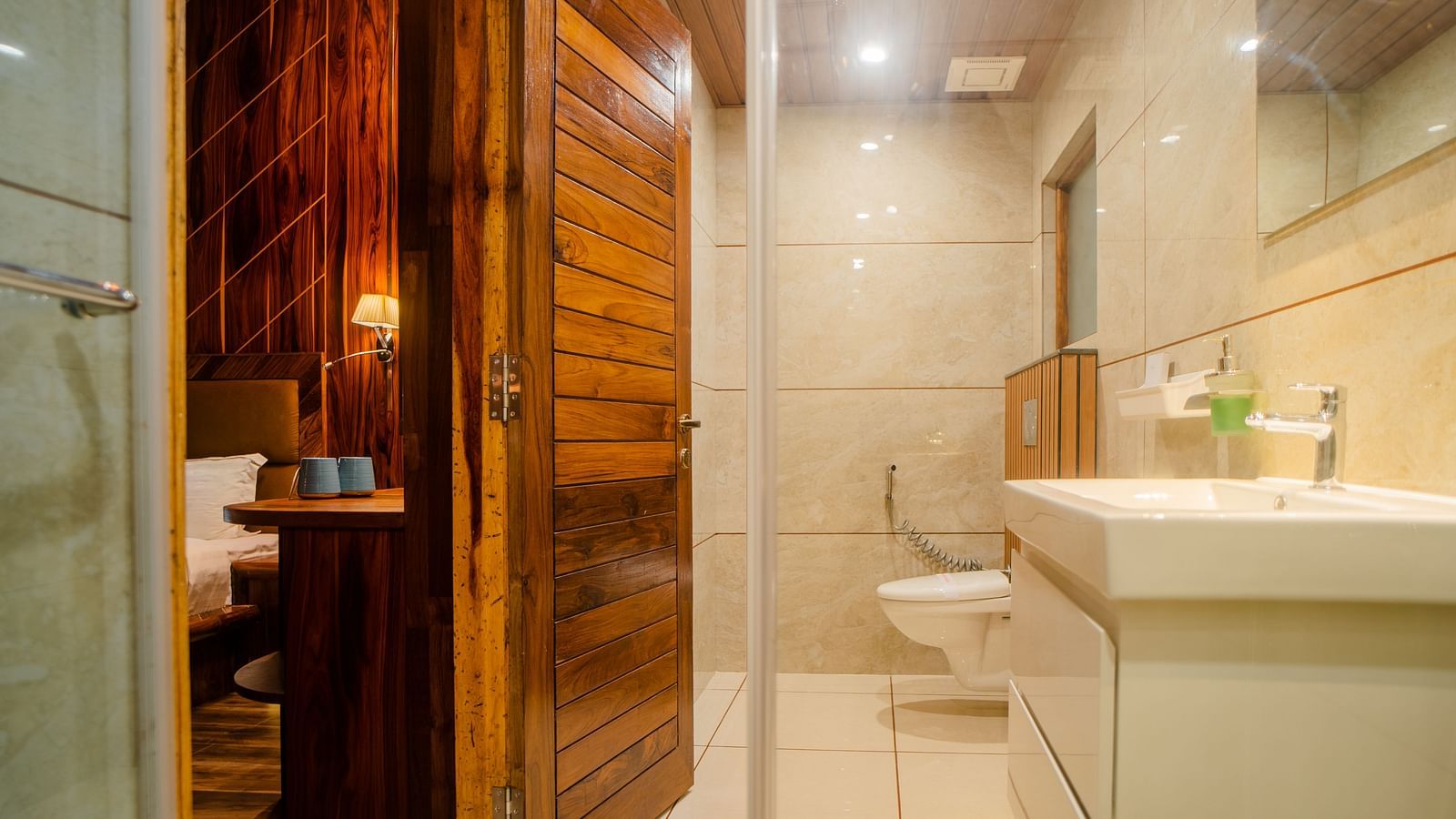 A view of a bathroom in a hotel with white tiles and a large sink with toiletries placed on it - Coral Reef Resort & Spa, Havelock