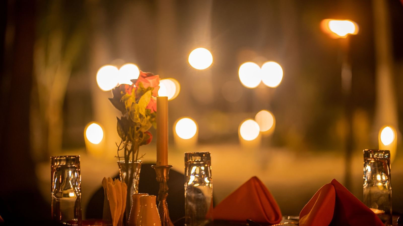 Close-up of a table setting with candles, flowers and warm lighting against an array of lights - Coral Reef Resort & Spa, Havelock