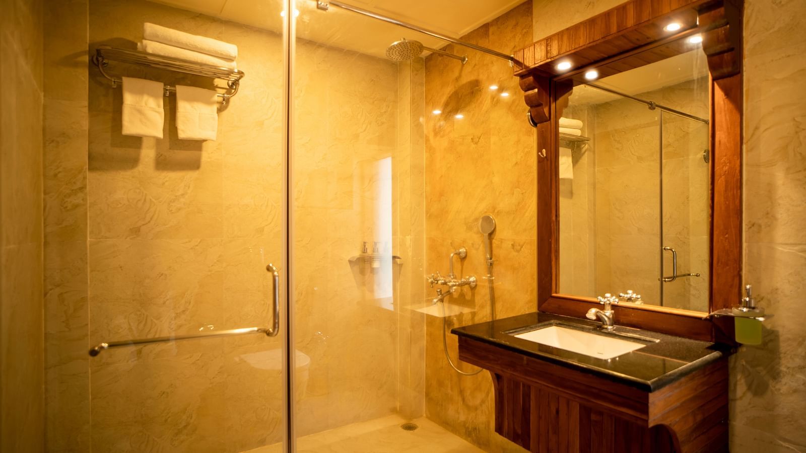 An image of a bathroom with a shower cubicle and a sink placed under a mirror illuminated by yellow light  - Coral Reef Resort & Spa, Havelock