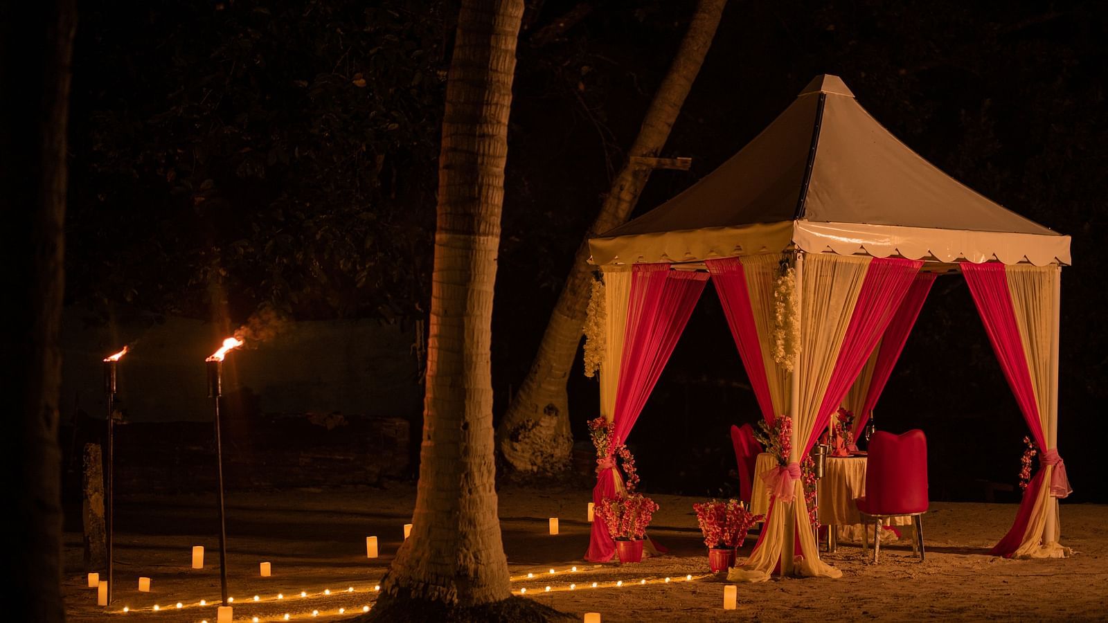 A romantic beachfront canopy lit by torches and candles at night - Coral Reef Resort & Spa, Havelock