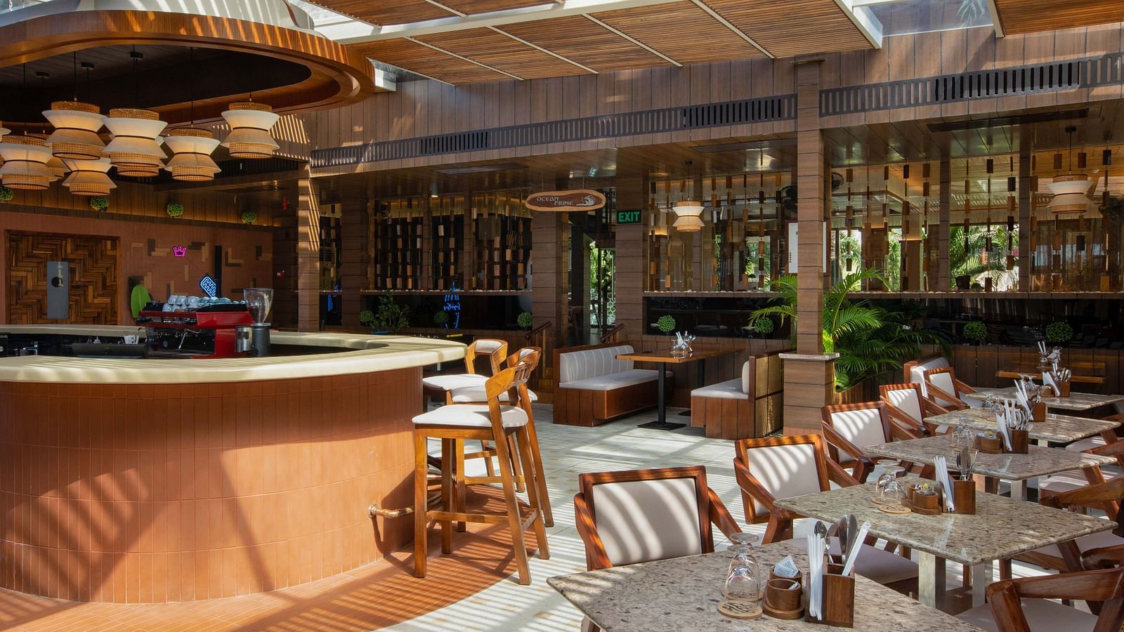 5th Bistro Cafe featuring a beautifully designed interior and dining area with wooden tables and chairs, suspended lighting fixtures, and tropical greenery. The space has a relaxed, elegant atmosphere - Coral Reef Resort & Spa, Havelock