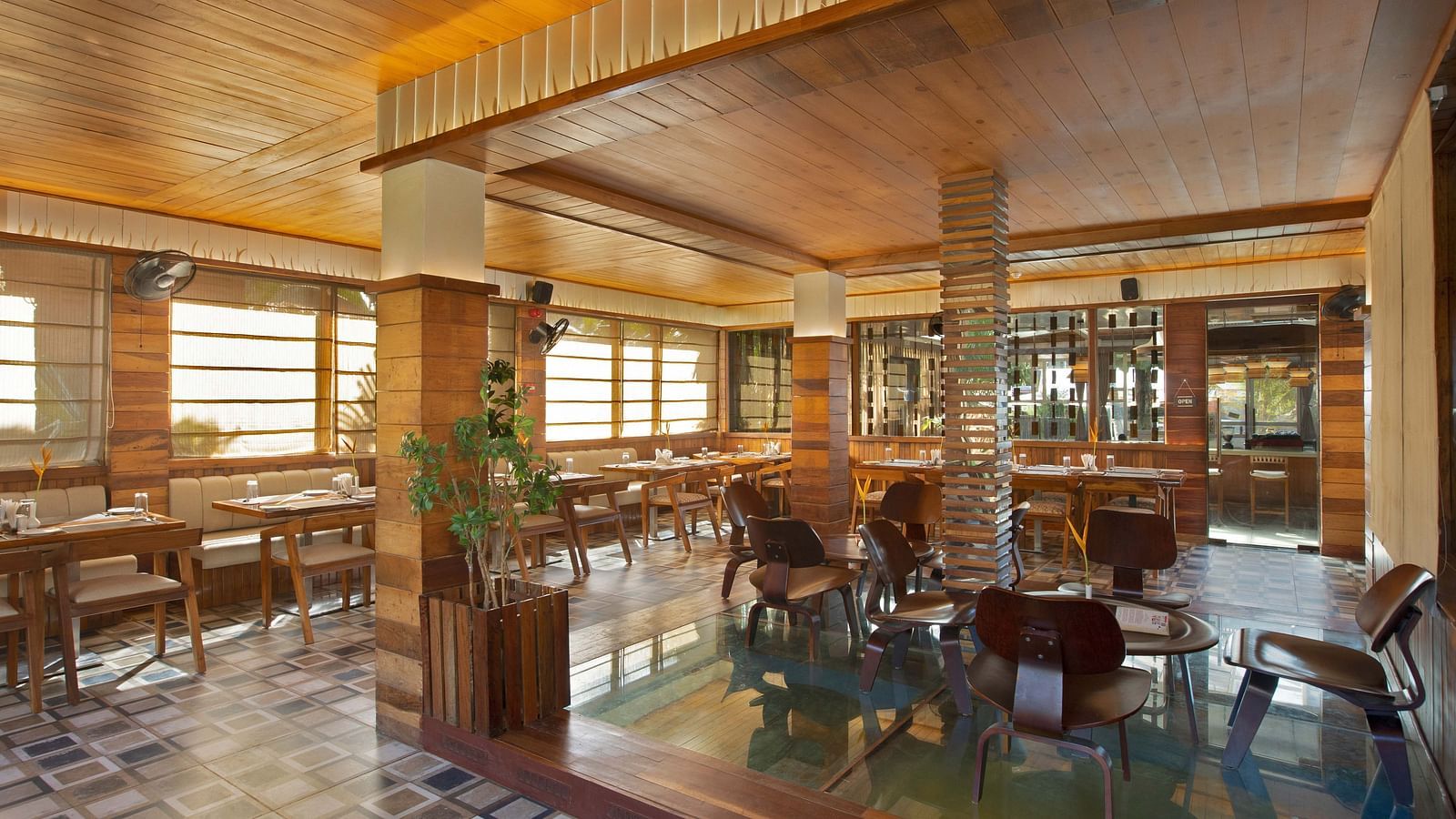 An elegant restaurant interior of Ocean Prime with wooden beams and tasteful decor. The space features a combination of dining tables and tropical plants, creating a warm, inviting vibe - Coral Reef Resort & Spa, Havelock