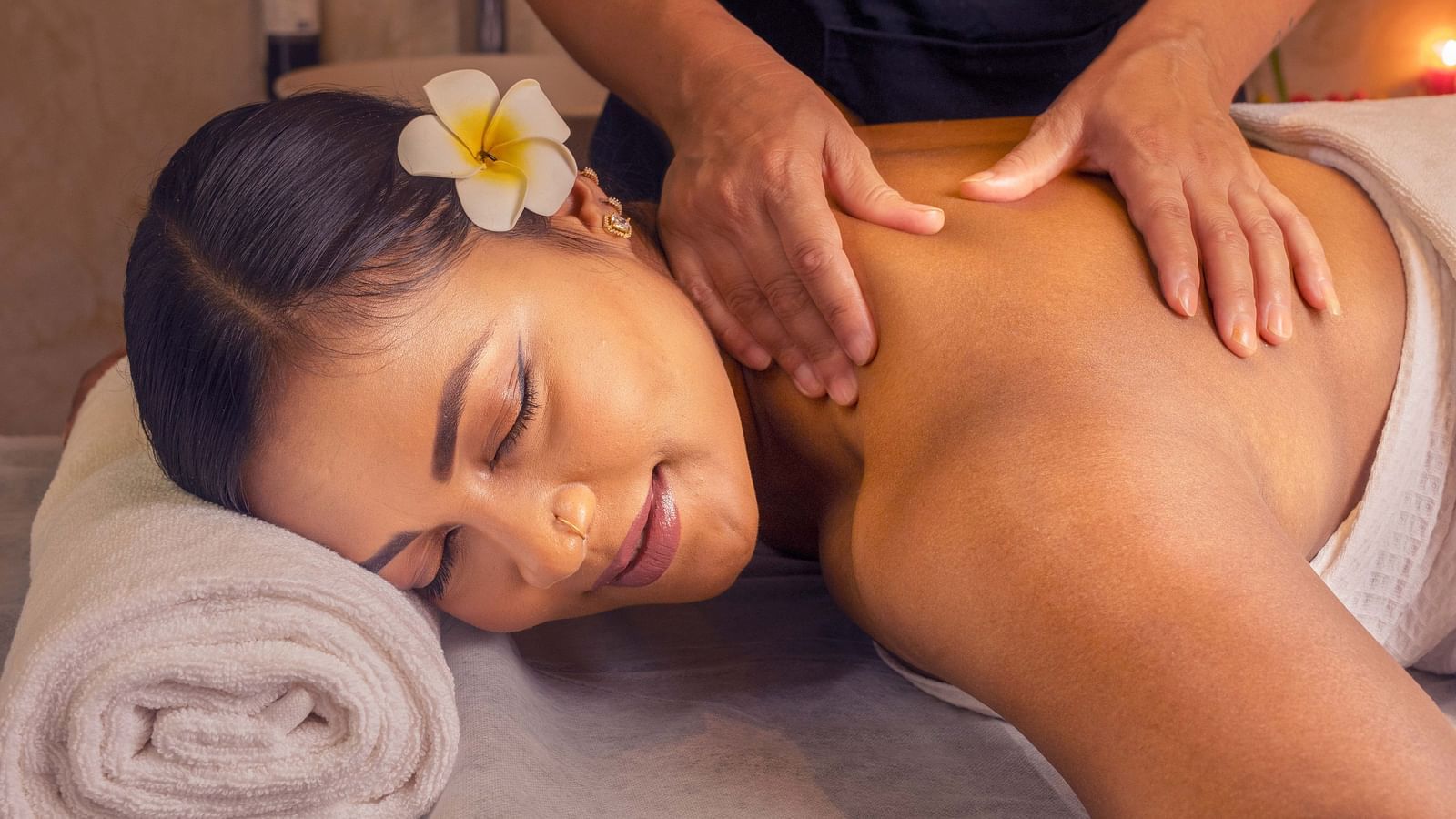 A woman receiving a soothing massage, surrounded by soft lighting and fresh flowers. The calm setting helps create a peaceful, spa-like experience - Coral Reef Resort & Spa, Havelock