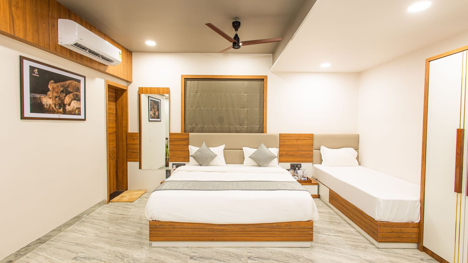 Wide view of the Daksh Pride room at Daksh Eden Greenz, Sasan Gir, showcasing its double, and single bed, wardrobe, and spacious layout.