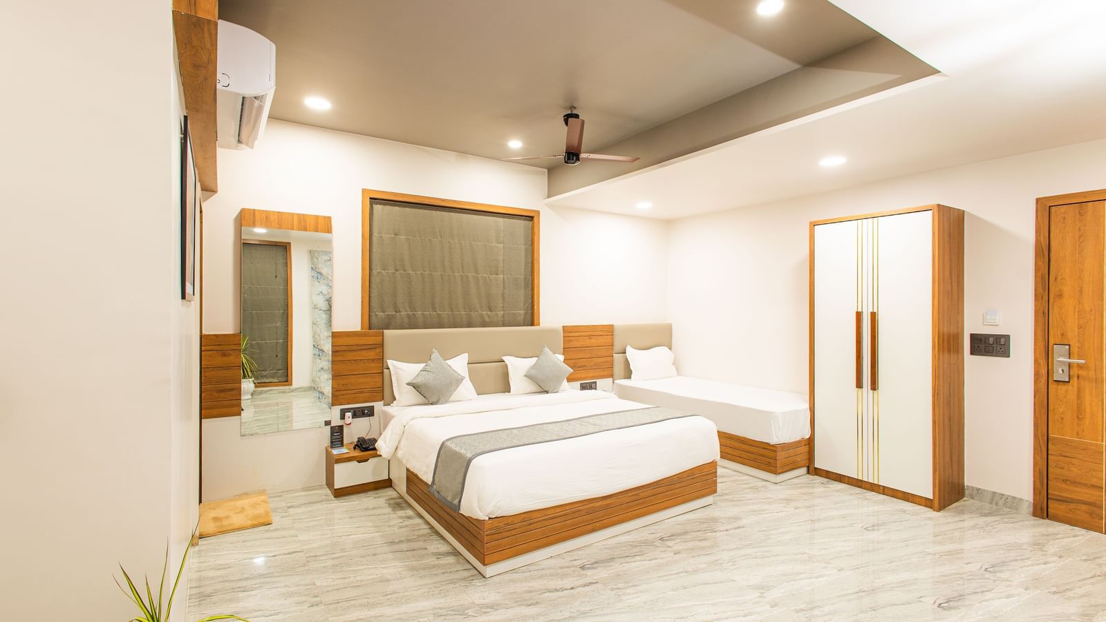 Wide view of the Daksh Pride room at Daksh Eden Greenz, Sasan Gir, showcasing its double, and single bed, wardrobe, and spacious layout.