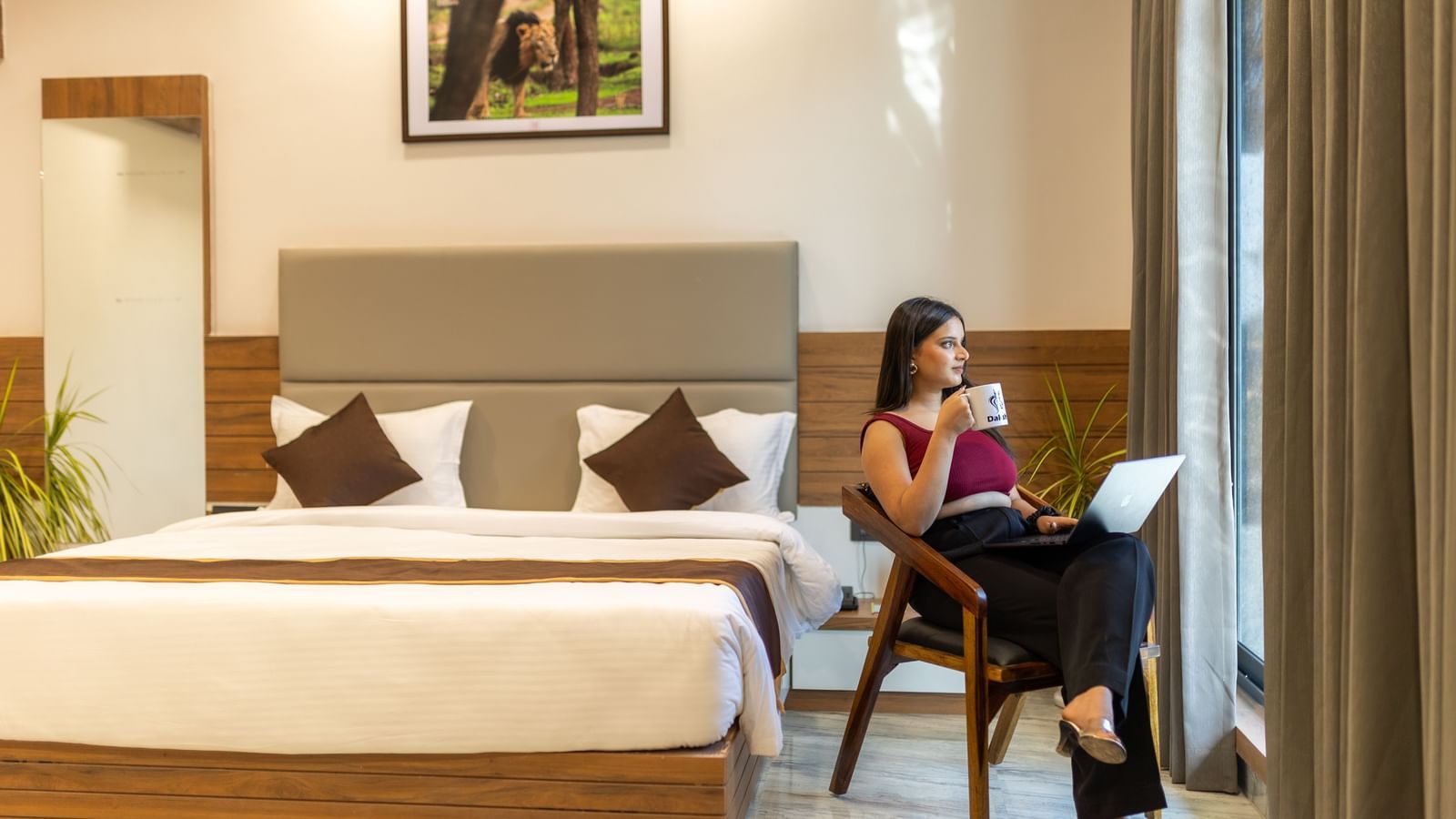 A girl sitting in the seating area of Daksh Bliss, also featuring a plush double bed, warm lighting | Daksh Eden Greenz, Sasan Gir