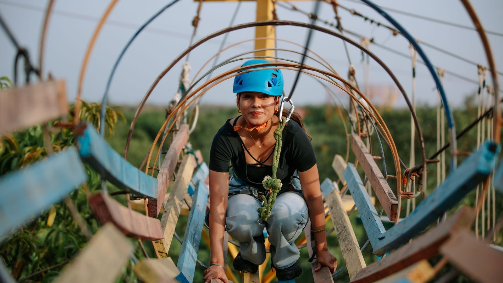 A girl inside a circular rope tunnel adventure structure at Daksh Resort & Amusement Park.