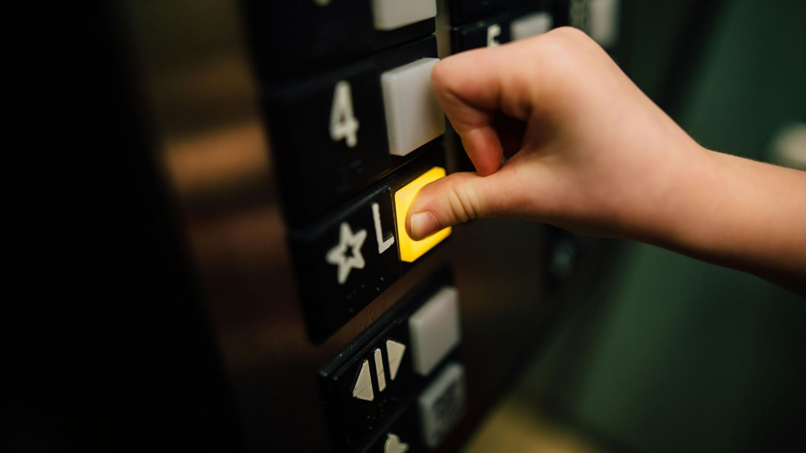 A close up shot of a person pressing the button inside an elevator.