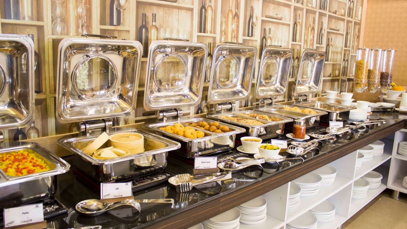 A close-up of a buffet with various dishes in chafing dishes | Daksh The Madhuvan Suites