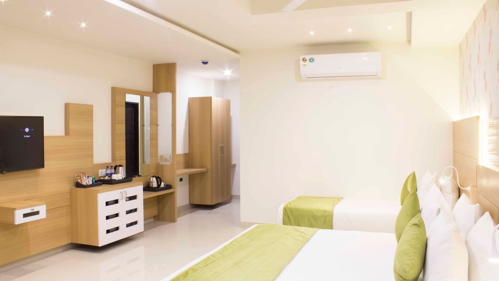 A hotel bedroom with a large bed, a single bed, with low headboards and a wall-mounted television | Daksh Pride Room | Daksh The Madhuvan Suites