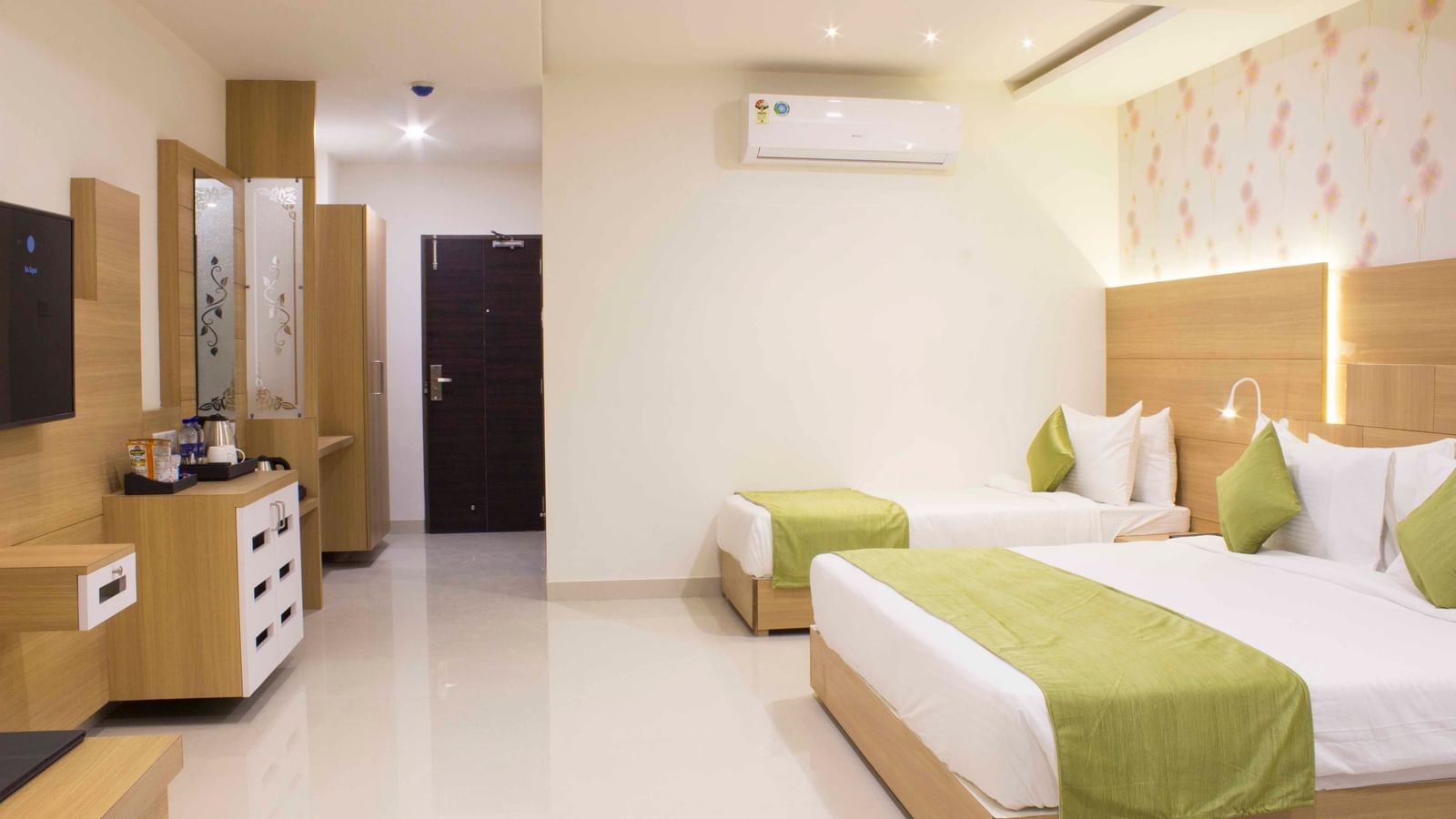 A hotel bedroom with a large bed, a single bed, with low headboards and a wall-mounted television | Daksh Pride Room | Daksh The Madhuvan Suites