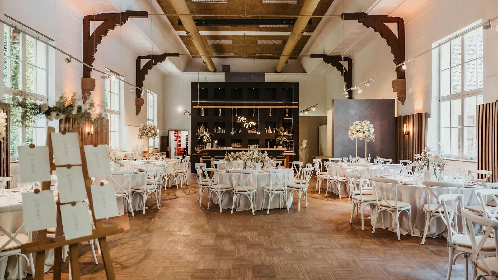 image of a banquet hall with well arranged tables and chairs decorated with flowers and cutlery 