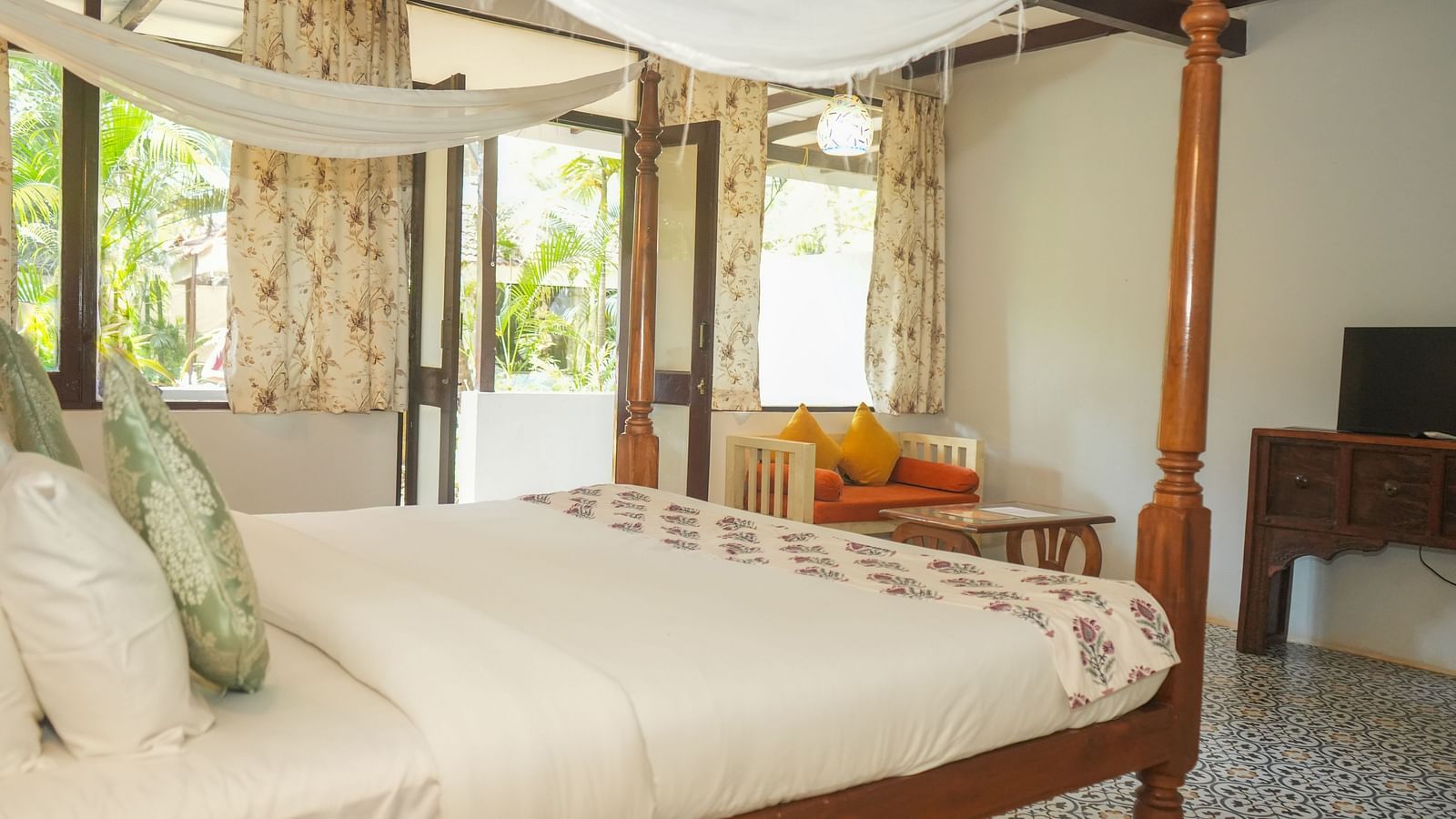 Side view of a canopy bed near large windows overlooking greenery at De Soul Santé, Morjim.