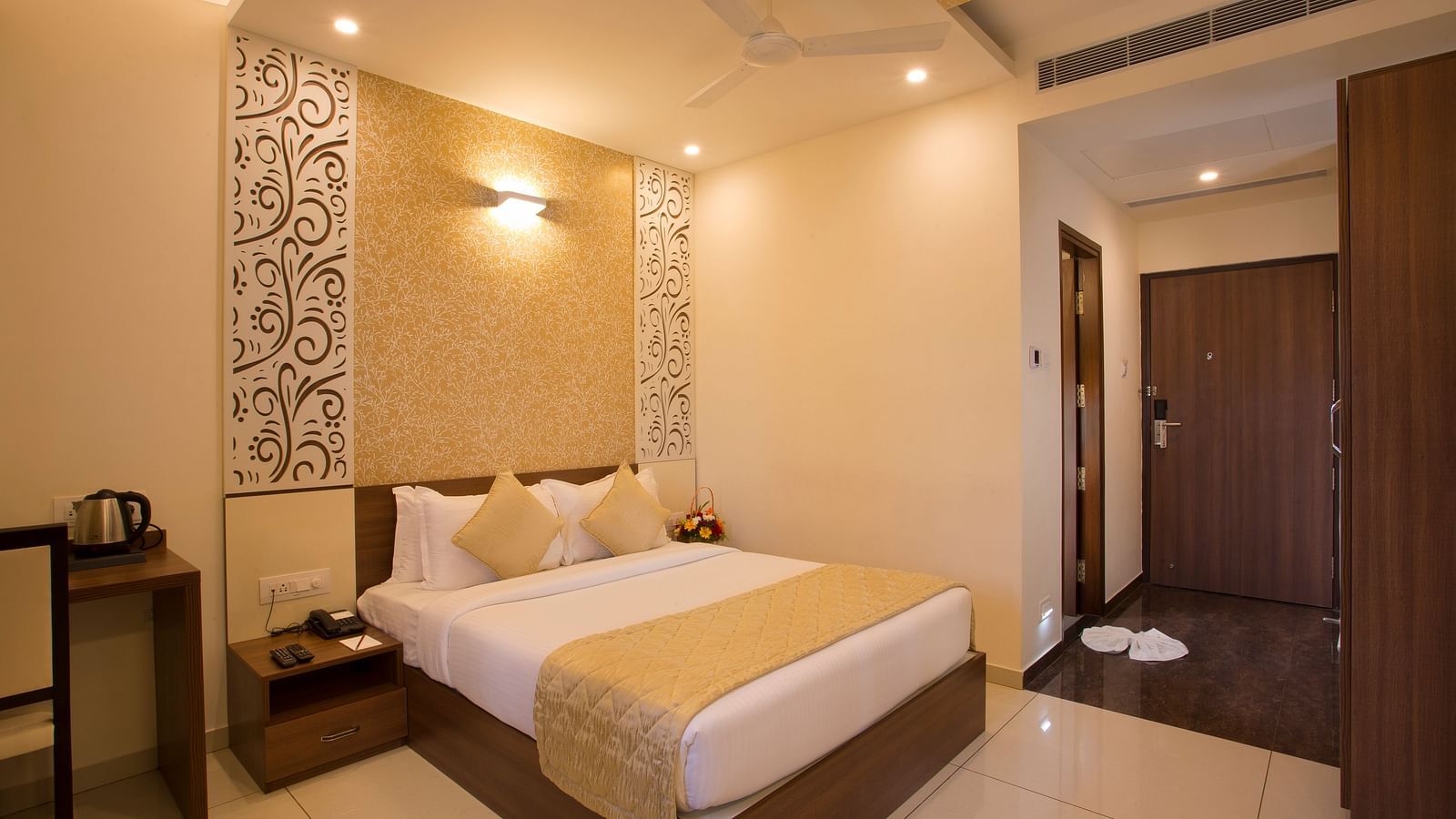 A hotel bedroom with a plush bed, decorative wallpaper and a view into the hallway - De Venetian by TGI, Brookefield