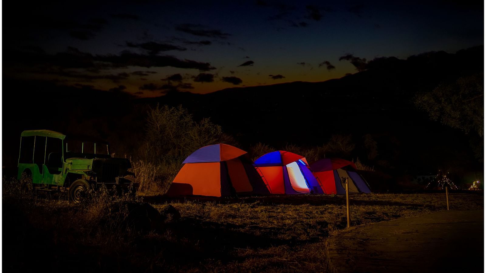 Illuminated camping tent set up on a mountain landscape under starry night sky  | Diamond Parks, Pune