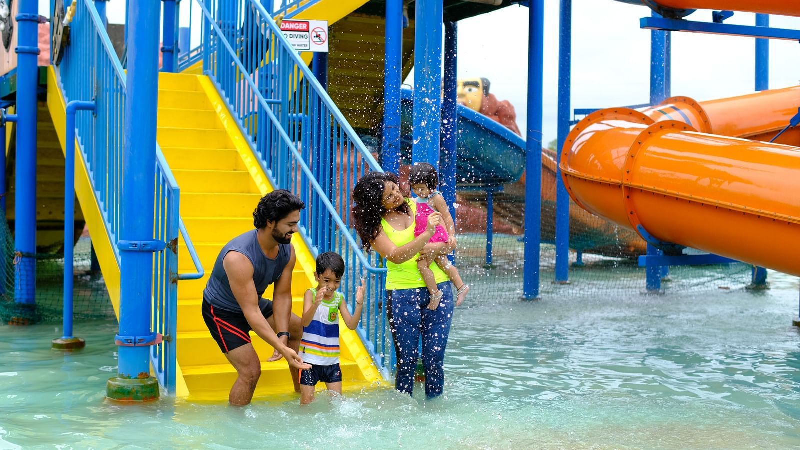 father helping his young child with a life jacket near water slides at a park | Diamond Parks, Pune 
