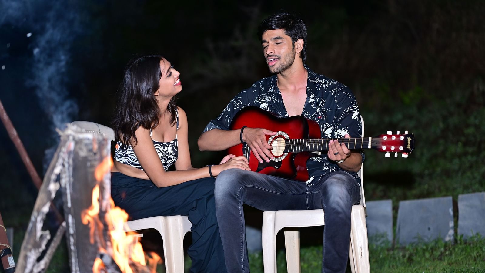 Couple playing guitar by a campfire at a camping site | Diamond Parks, Pune