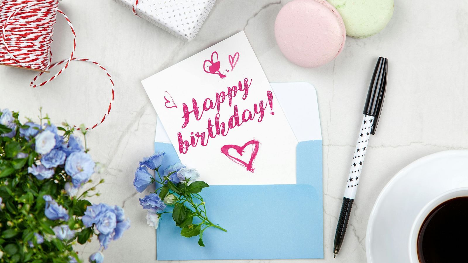 A happy birthday card placed on a table besides a marker and a cup of coffee