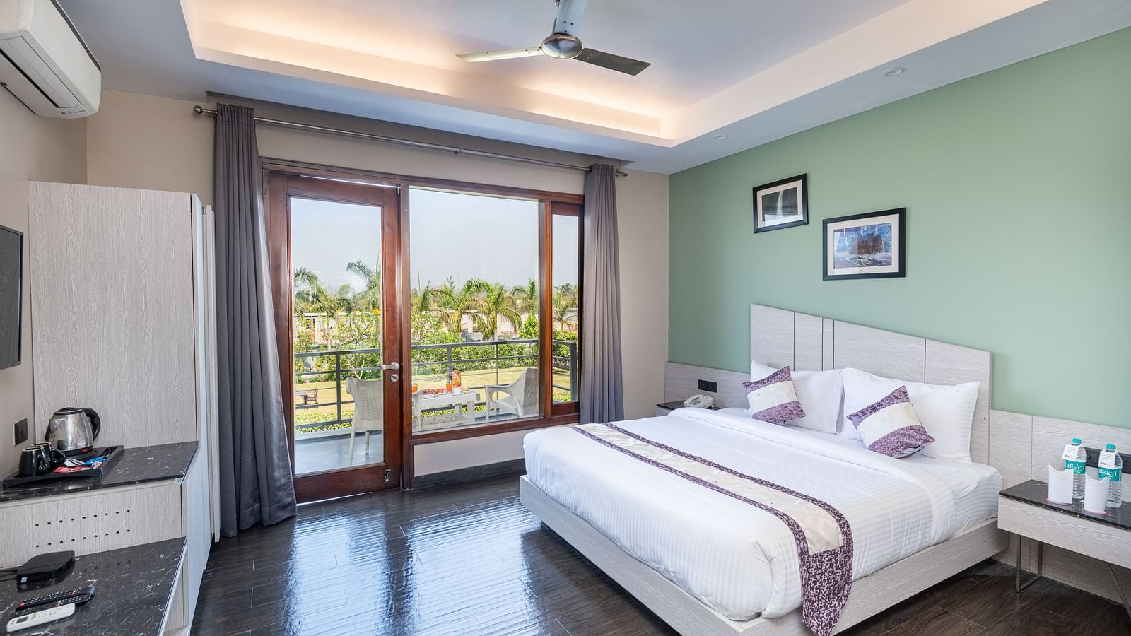 Spacious room at DLS Forest Vines Resort featuring a large bed, a bedside table, and a large glass door leading to the balcony.