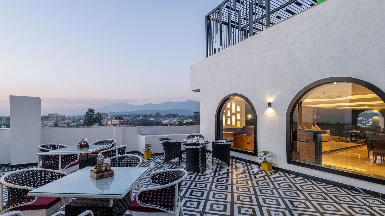 Image of rooftop restaurant Ruttba at DLS Grand Luxotica, Dehradun featuring dining setting on a well furnished floor with the scenic view of Dehradun city