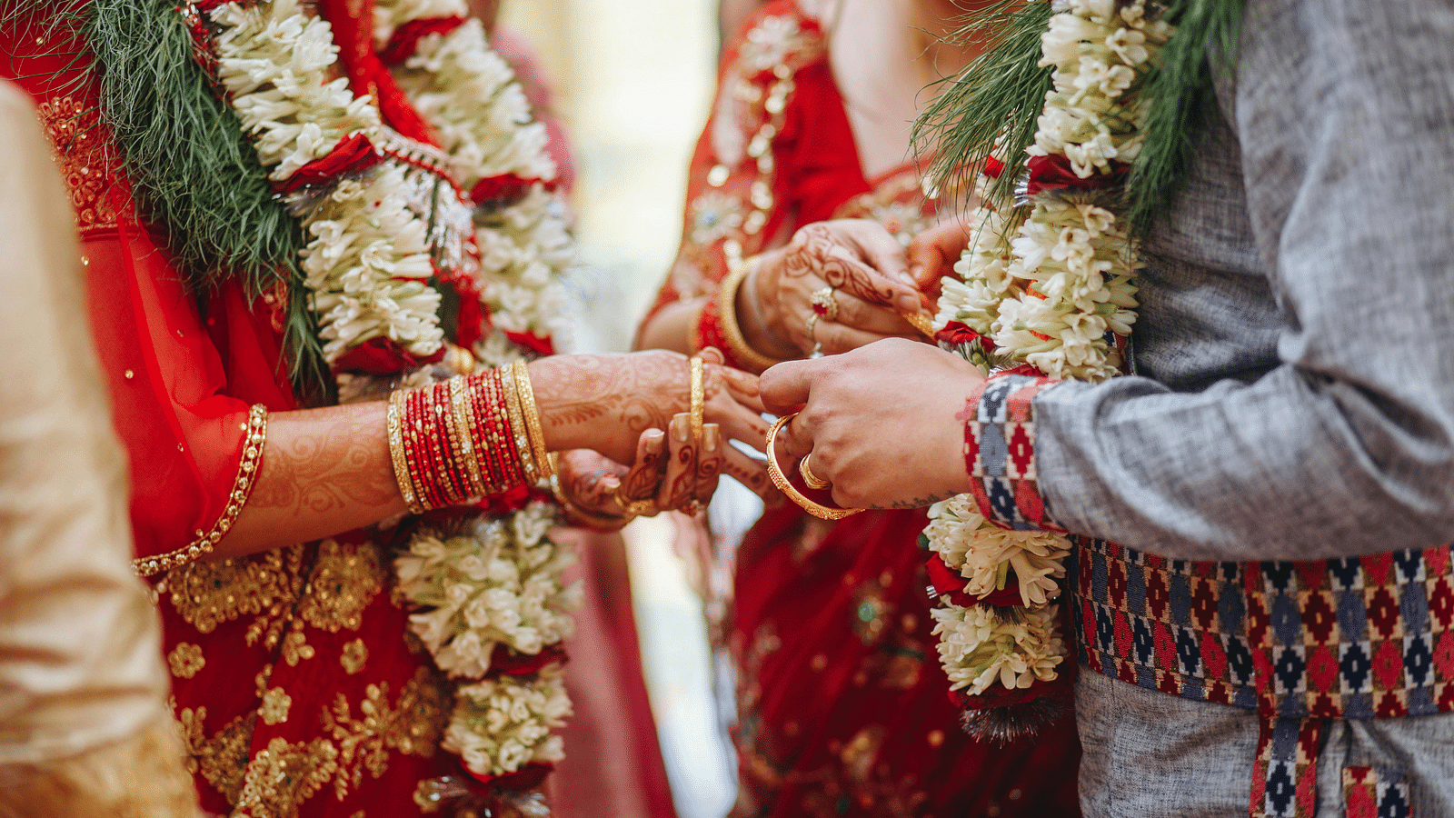 a couple wearing flower garlands exchanging rings during the wedding ceremony