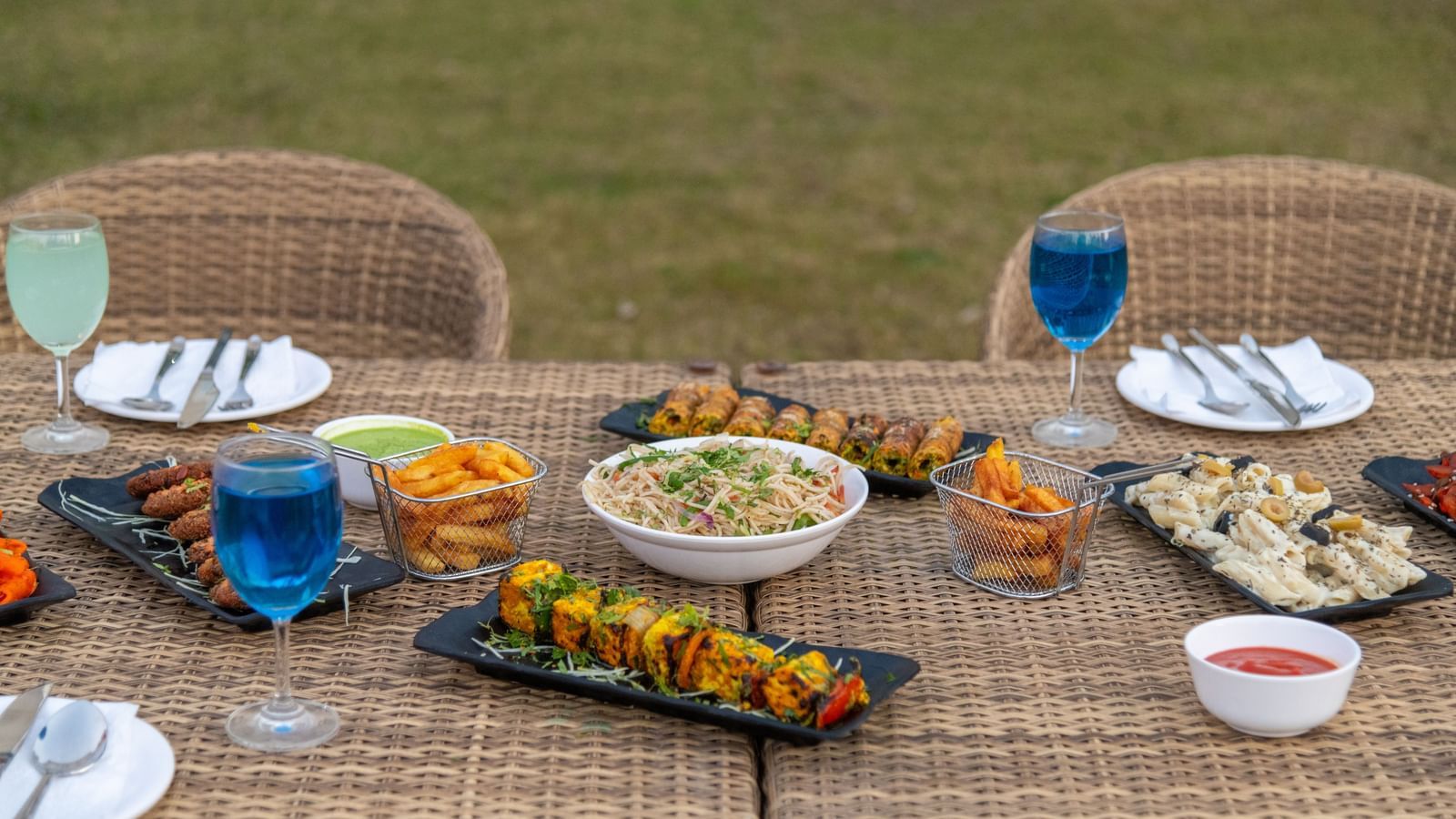 Outdoor dining setup with food and beverages on a long table at DLS Park Grace, Haridwar.