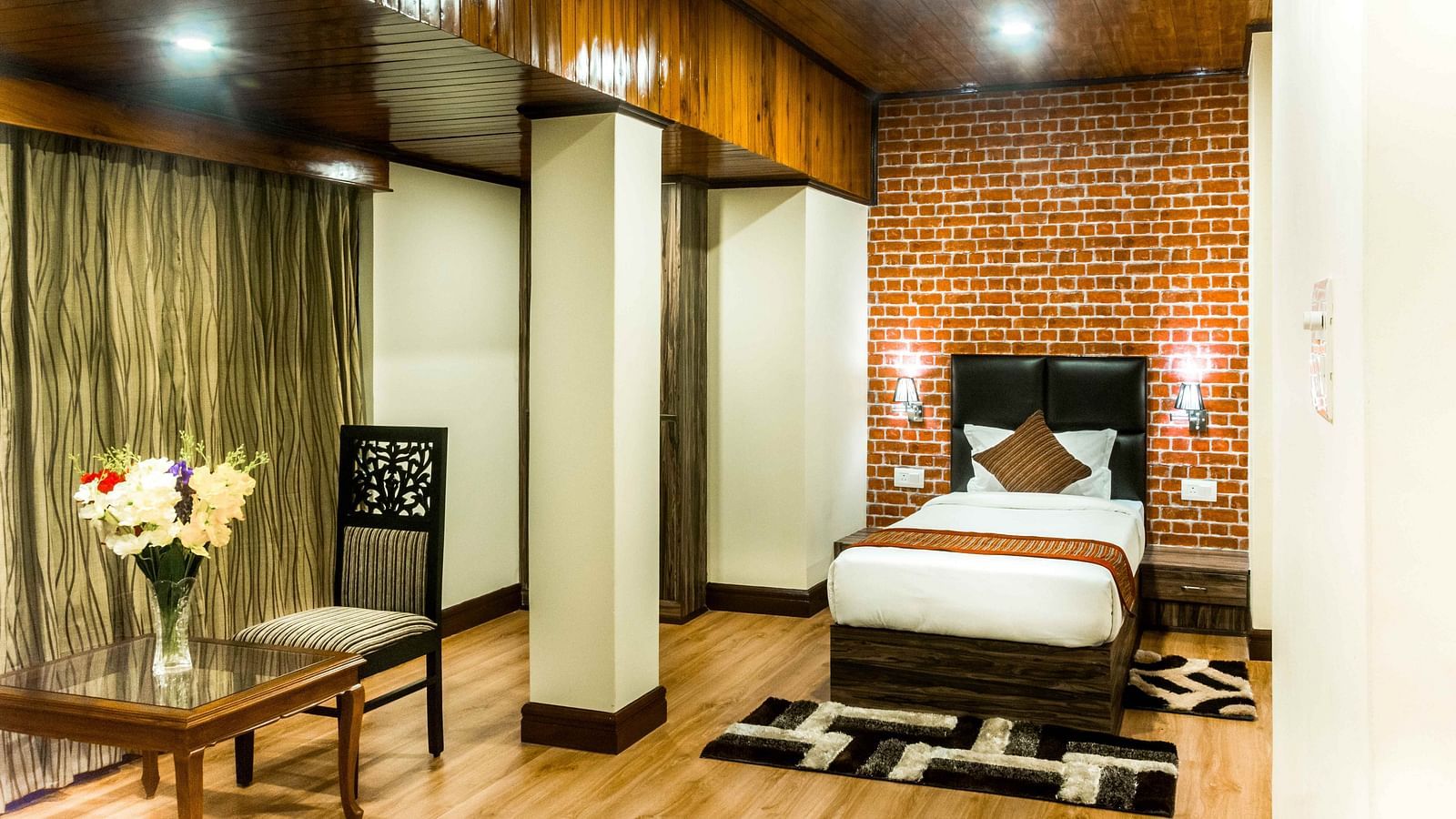 An image of a suite at the Ecotel Tin Tin, Bijanbari featuring a single bed, bed side tables, a table and a chair and other amenities